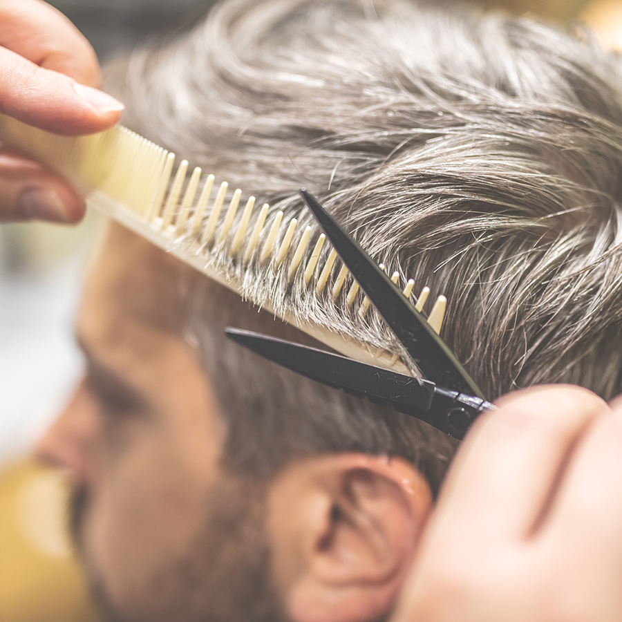 Man in barber chair, hairdresser styling his hair.
