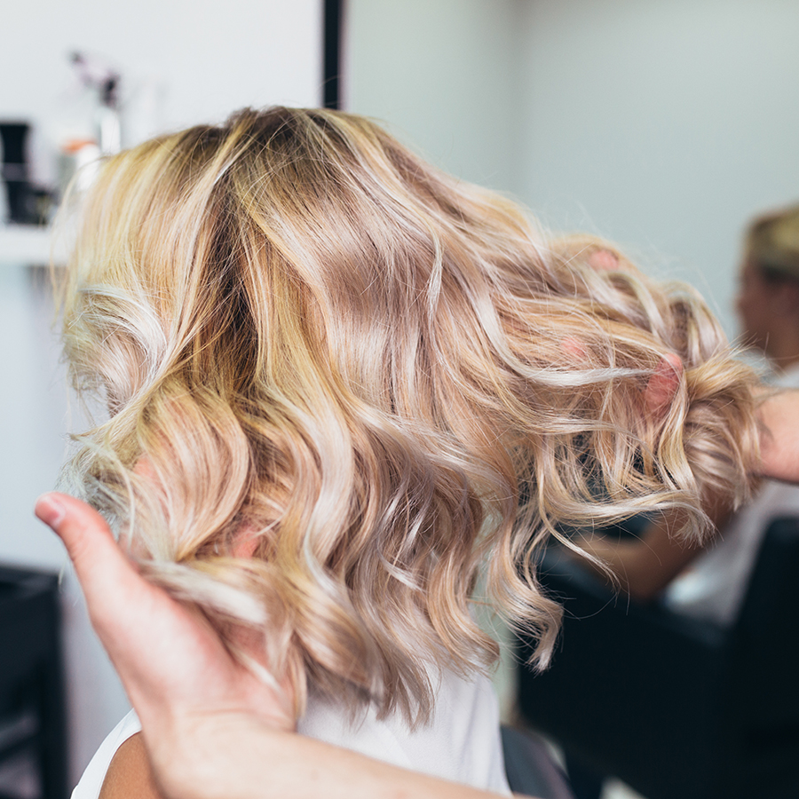 Beautiful hairstyle of a young woman after dying hair. blonde wavy medium length.
